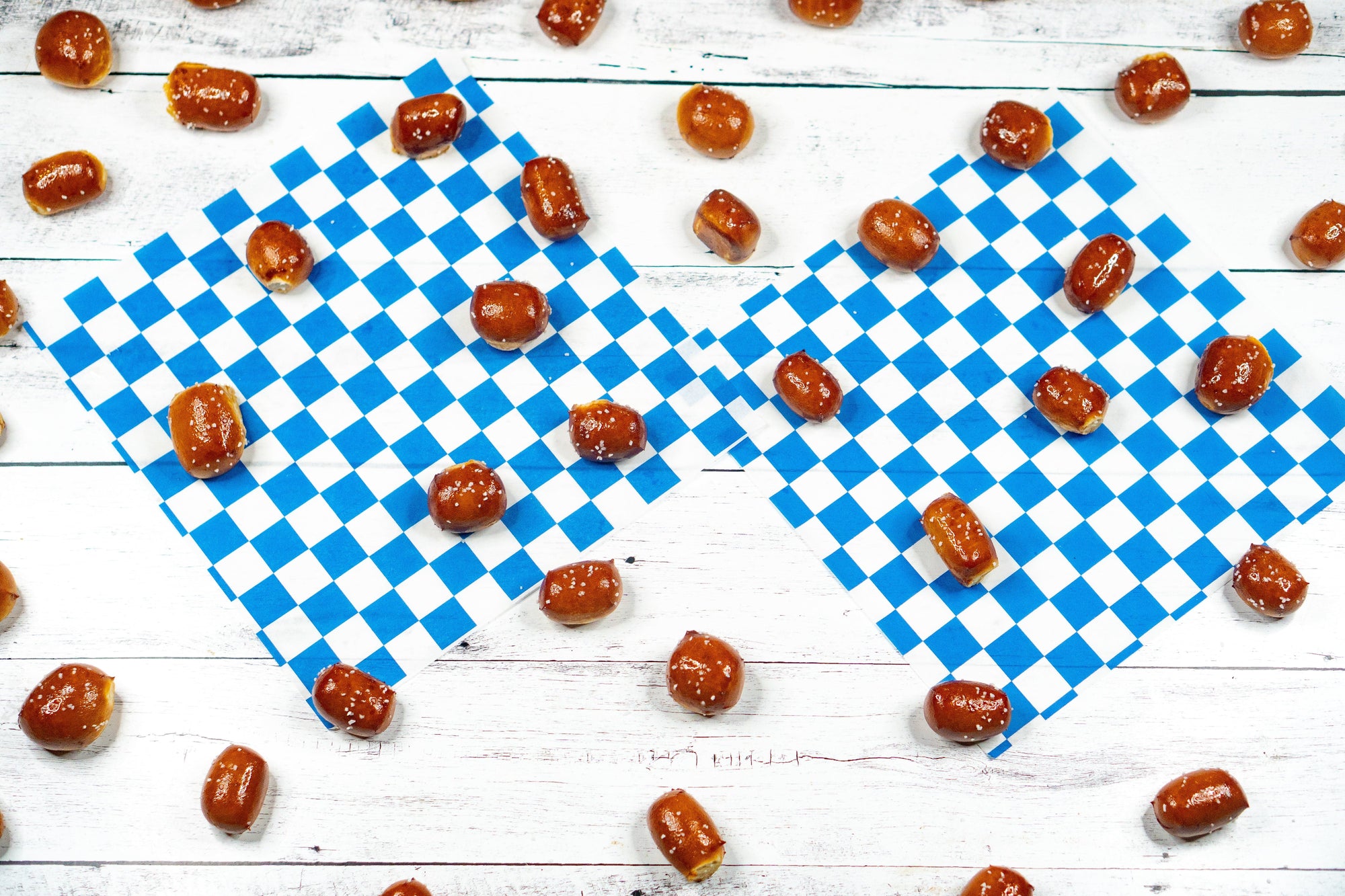 Pretzel nuggets on a blue and white checkered cloth with scattered candies on a wooden surface