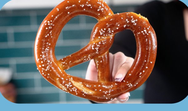 a hand holding a salted soft pretzel