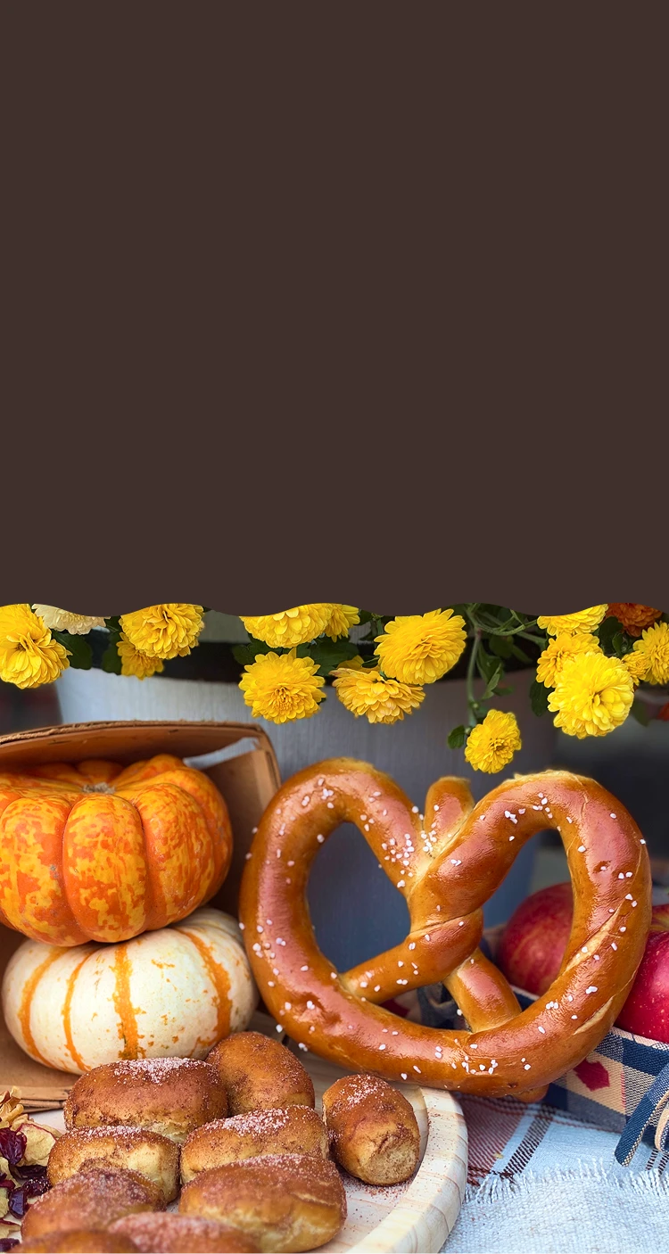a stack of pumpkin-shaped soft pretzels on a candlelit fall table with pumpkins and lanterns